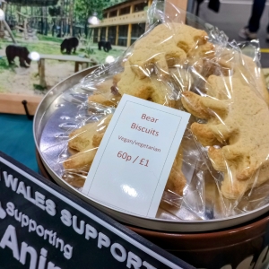 Bear-shaped vegan biscuits for sale at an animal charity event, with a photo of bears in the background.