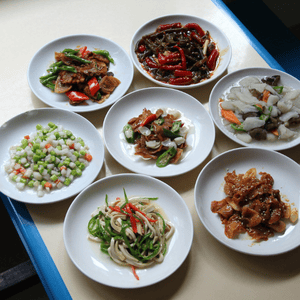 Seven vegan dishes displayed in a circle on white circular plates