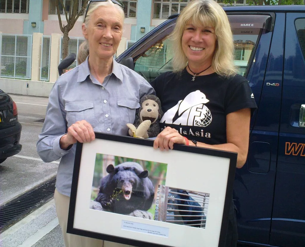 Dr Jane Goodall and Jill Robinson together holding a framed photo of a bear