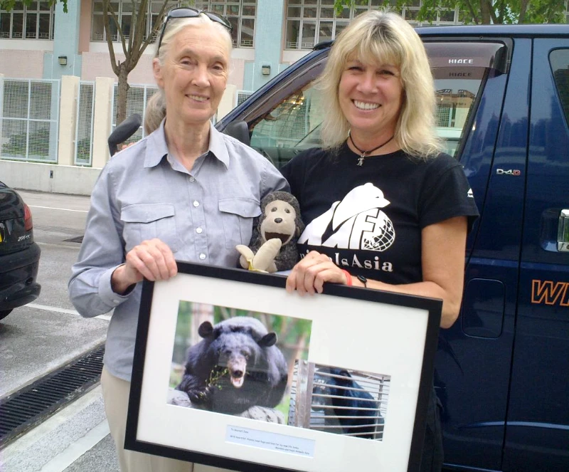 Jane Goodall and Jill Robinson holding a framed photo of a bear