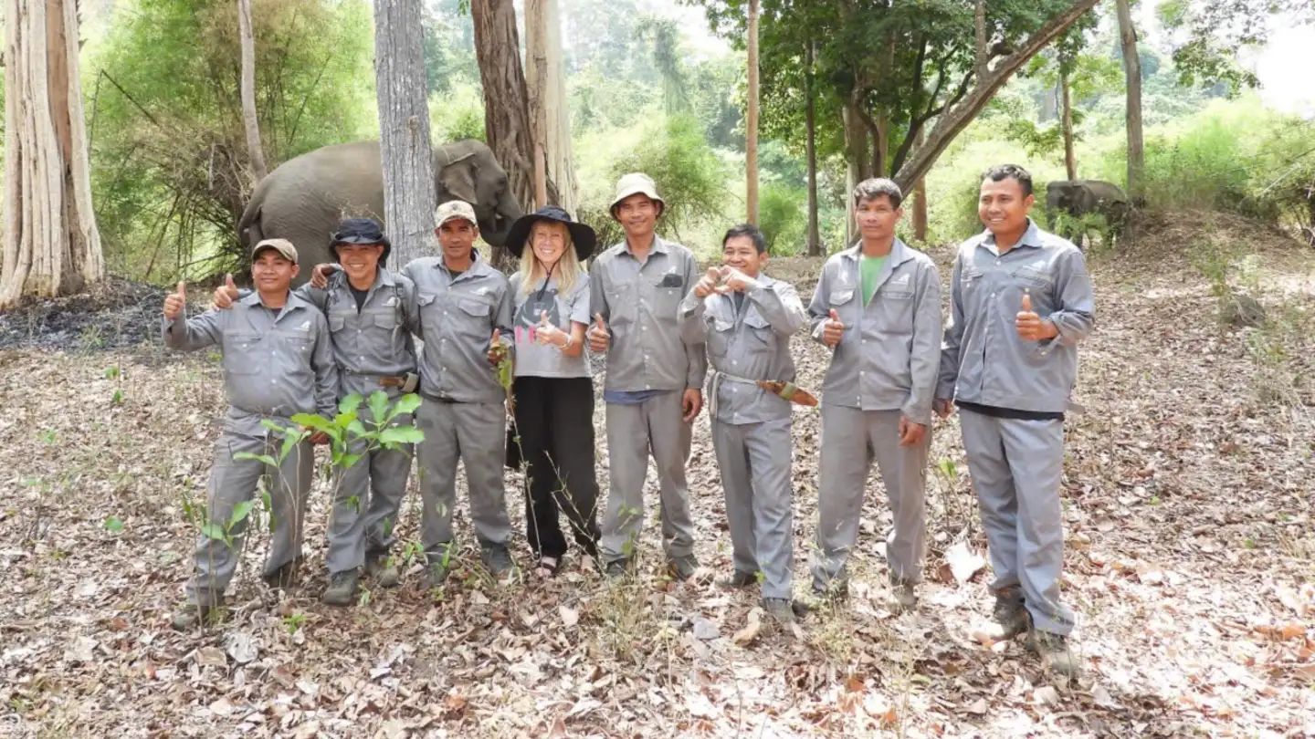 Jill Robinson standing in a forest with a group of mahouts